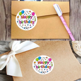 Happy Birthday stickers on brown paper with a pen and ribbon.